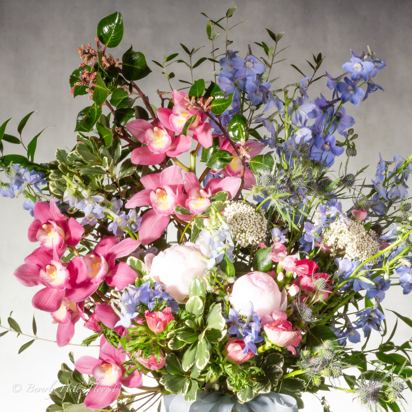 A Floral Tale of Love and Beauty with pink cymbidium orchids and delphiniums in a tall glass vase, available for same-day delivery by Beverly Hills Florist.