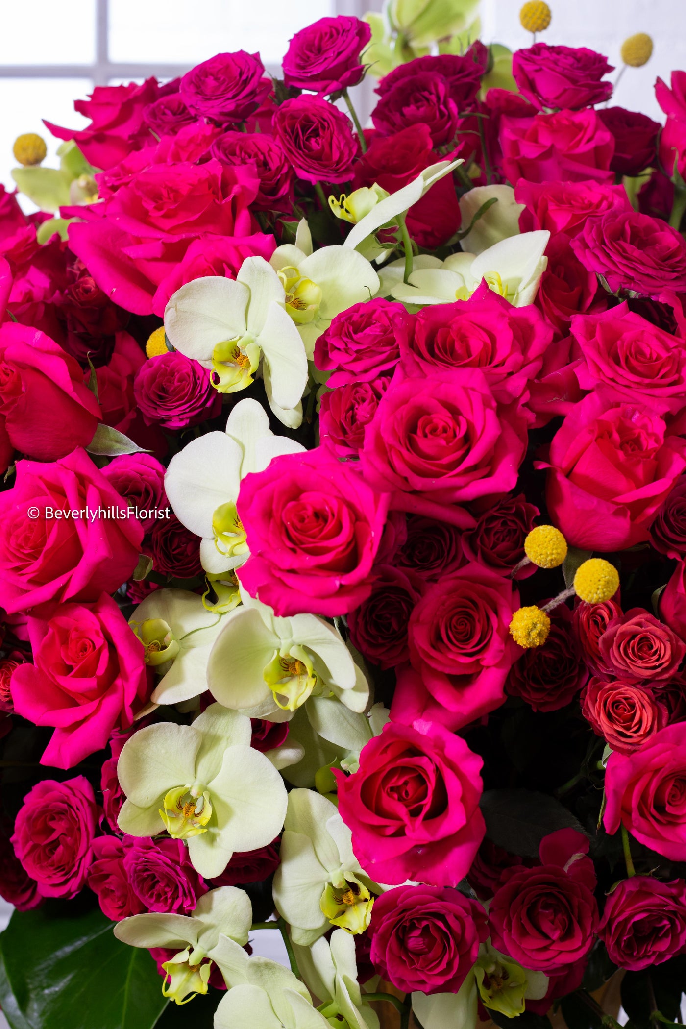 Amore Roses arrangement with red and pink Ecuadorian roses, spray roses, and orchids in a golden pedestal container, 40-inch round, elegant and romantic.