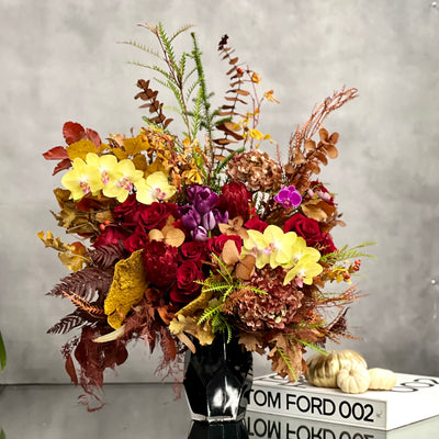 Autumn Harmony arrangement with fall flowers in vibrant reds, oranges, yellows, and browns, set in a black geometric vase, available for same-day delivery by Beverly Hills Florist.