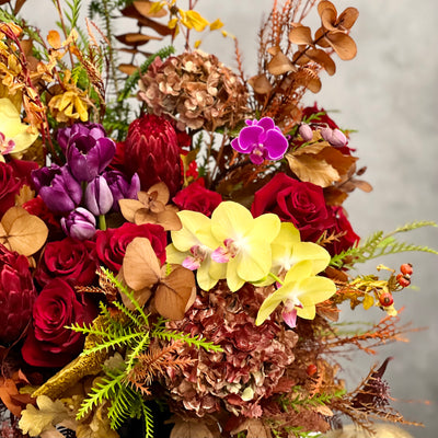 Autumn Harmony arrangement with fall flowers in vibrant reds, oranges, yellows, and browns, set in a black geometric vase, available for same-day delivery by Beverly Hills Florist.