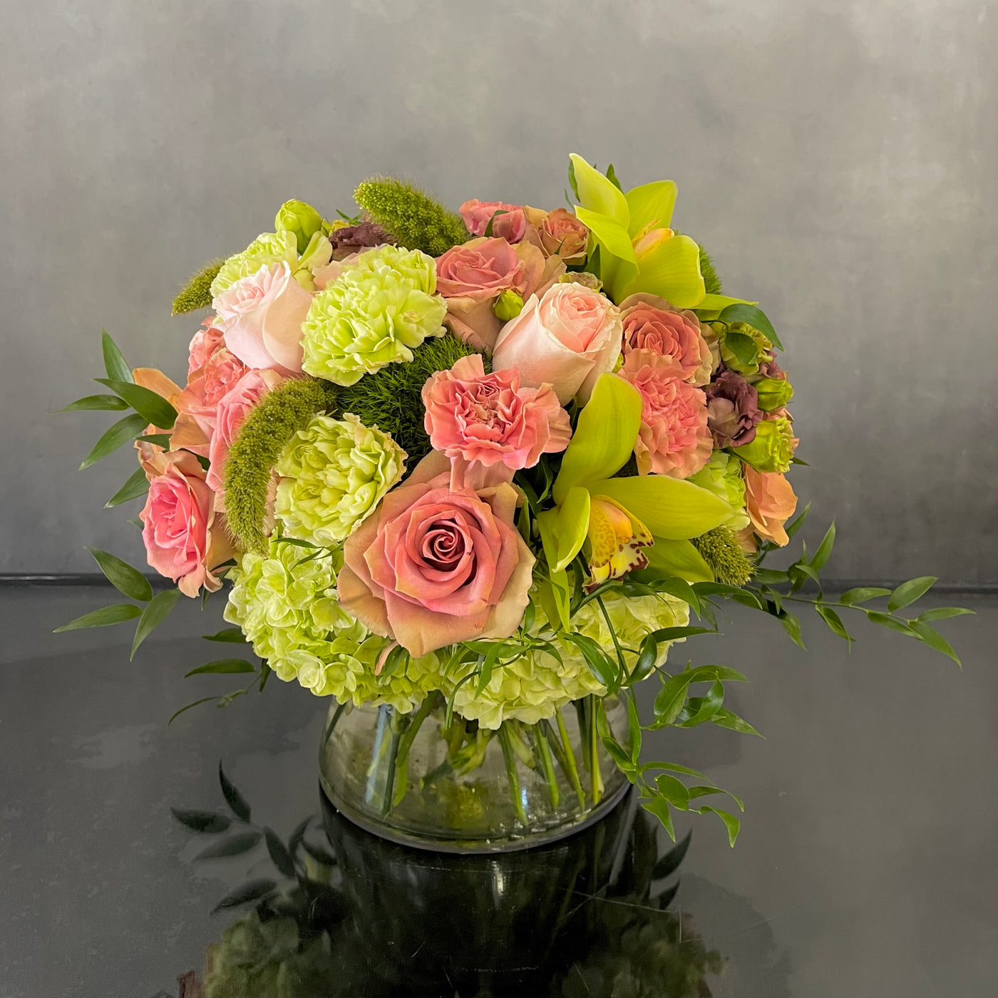 Beautiful Garden arrangement with pink roses, green and peach orchids, hydrangeas, and dianthus in a 6x6 cylinder vase, available for same-day delivery by Beverly Hills Florist.