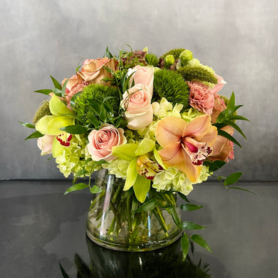 Beautiful Garden arrangement with pink roses, green and peach orchids, hydrangeas, and dianthus in a 6x6 cylinder vase, available for same-day delivery by Beverly Hills Florist.