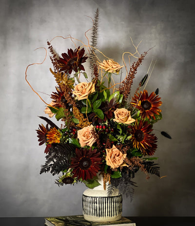 Black Sun arrangement featuring bold sunflowers in a white ceramic vase with black lines, available for same-day delivery by Beverly Hills Florist.