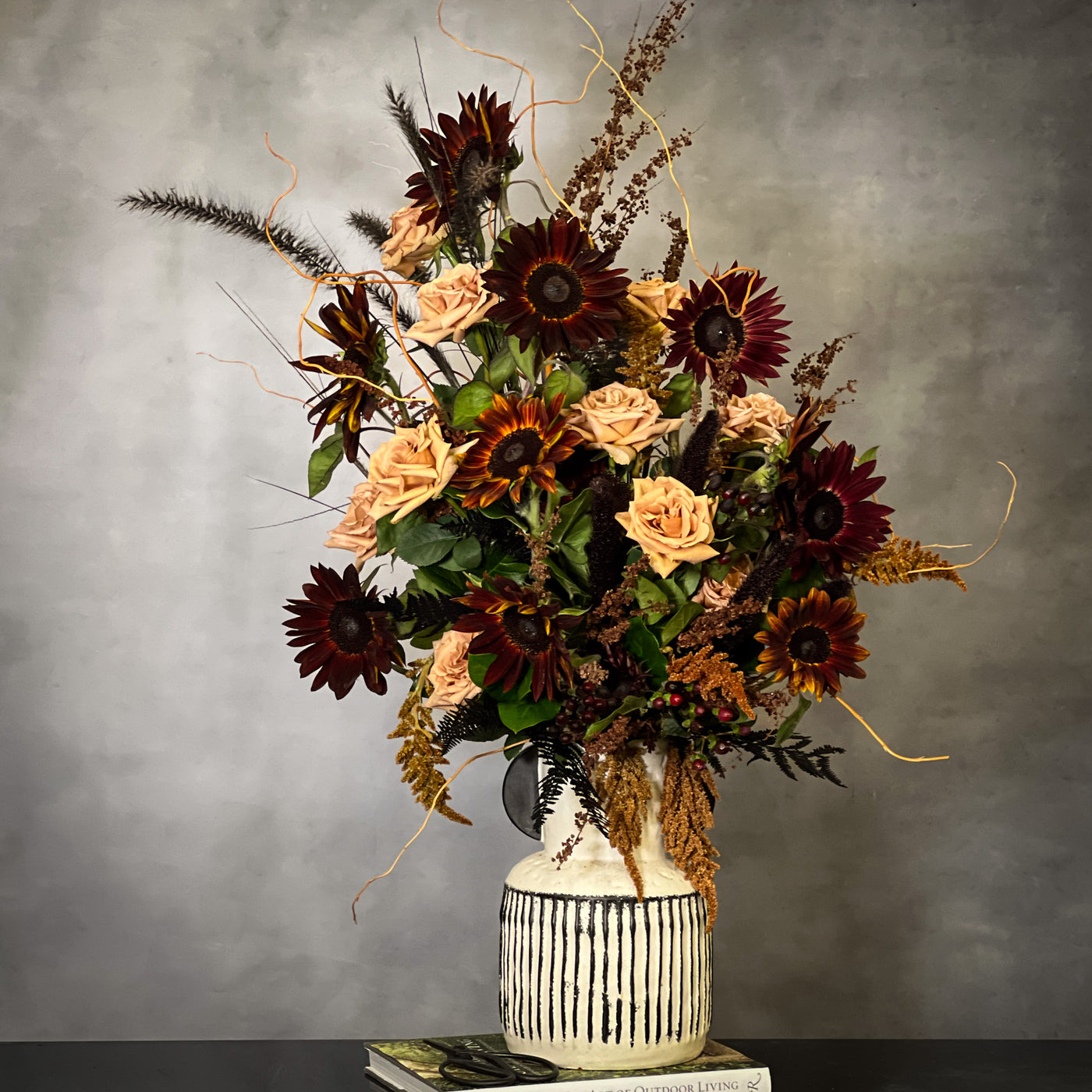 Black Sun arrangement featuring bold sunflowers in a white ceramic vase with black lines, available for same-day delivery by Beverly Hills Florist.