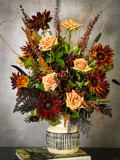 Black Sun arrangement featuring bold sunflowers in a white ceramic vase with black lines, available for same-day delivery by Beverly Hills Florist.