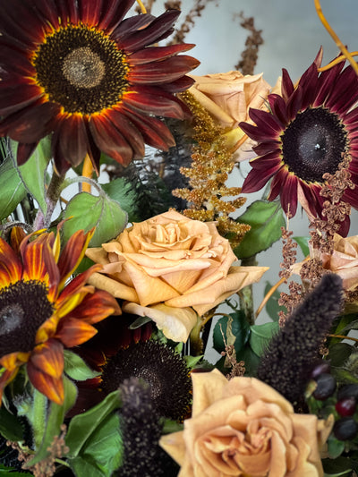 Black Sun arrangement featuring bold sunflowers in a white ceramic vase with black lines, available for same-day delivery by Beverly Hills Florist.