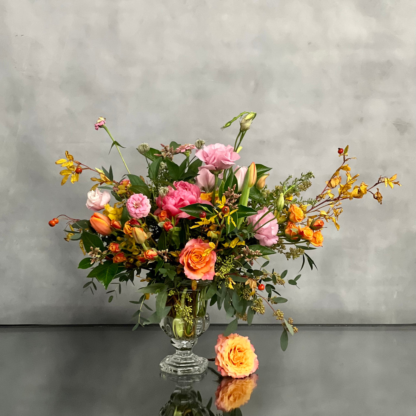 Blossoms Of The Roaring Twenties arrangement with orange garden roses, coral peonies in a vintage 20's era vase, available for same-day delivery by Beverly Hills Florist.