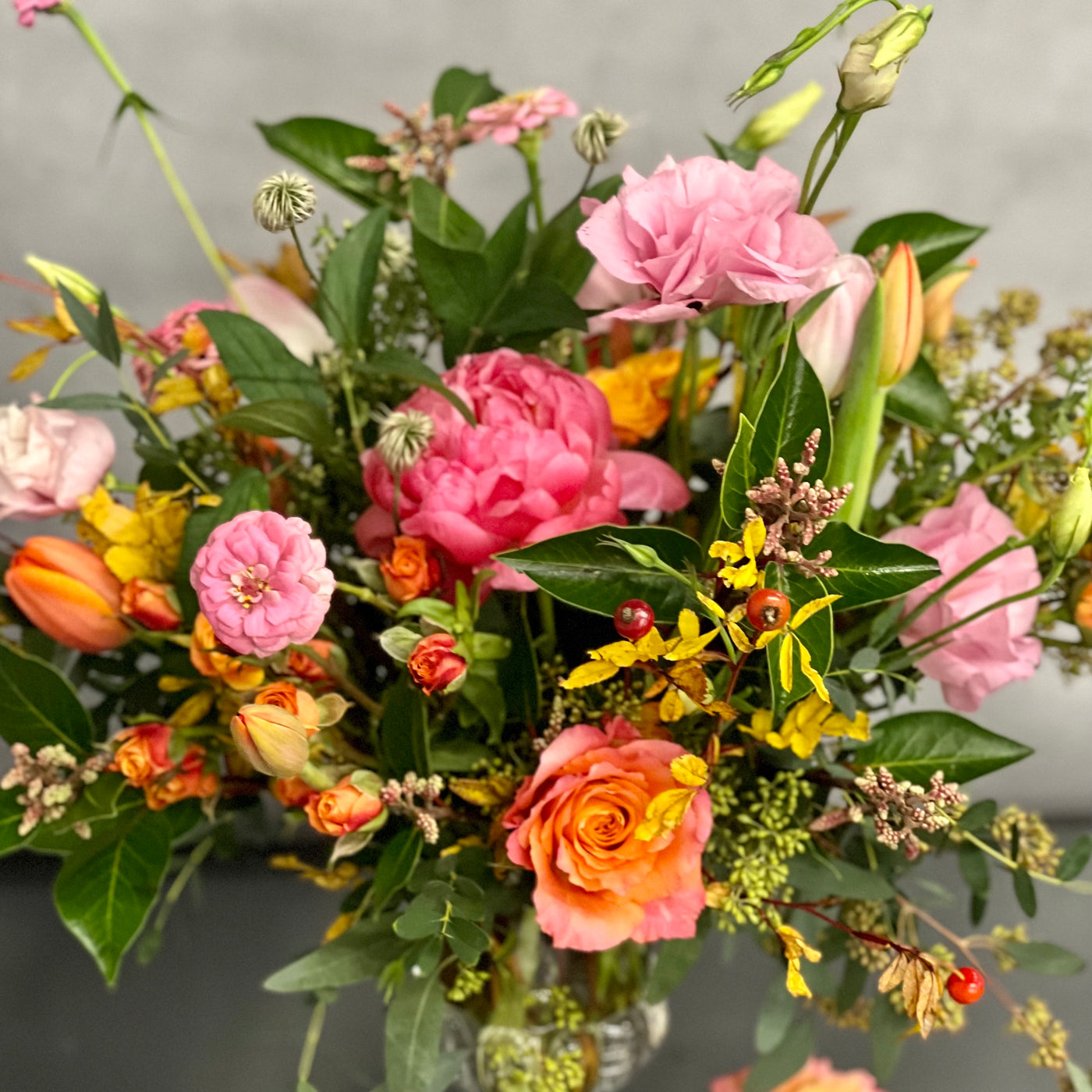 Blossoms Of The Roaring Twenties arrangement with orange garden roses, coral peonies in a vintage 20's era vase, available for same-day delivery by Beverly Hills Florist.