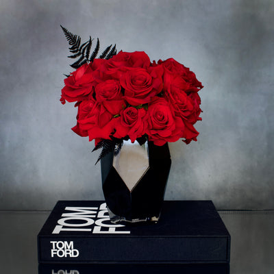 Deep red roses in a black geometric glass vase, measuring 14x9 inches, modern and elegant floral arrangement.