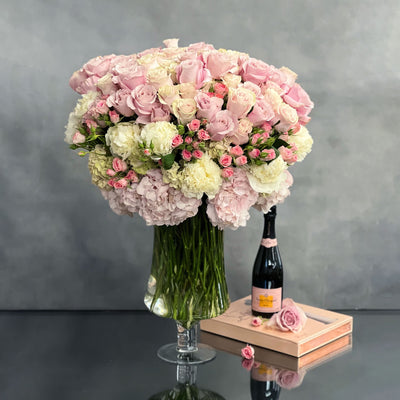 Elegant arrangement of over 100 pale pink roses and peonies in a sleek glass vase, 28 inches tall, designed by Beverly Hills Florist.