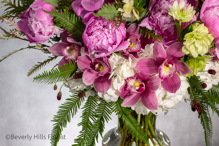 Elegant Floral Fusion arrangement with peonies, cymbidium orchids, and white hydrangeas in a tall glass vase – available for same-day delivery by Beverly Hills Florist.