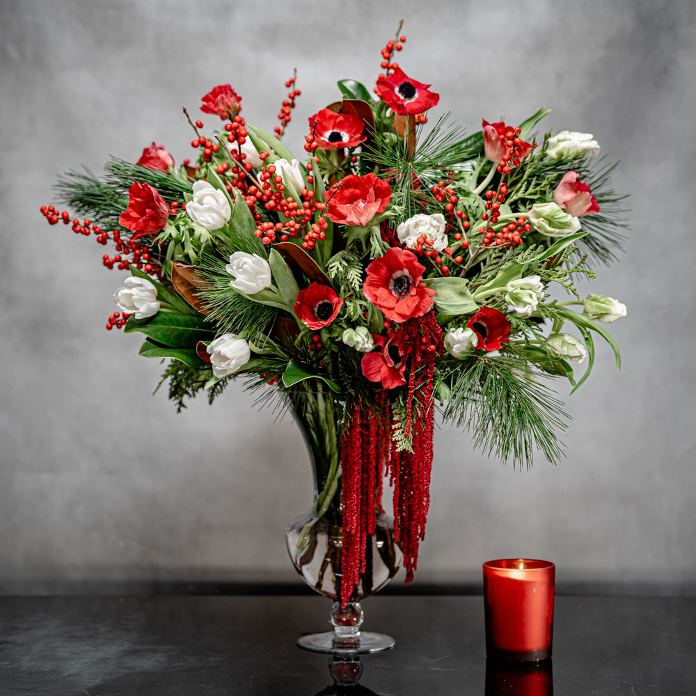 Christmas arrangement with red anemones, white tulips, Ilex berries, and winter greens