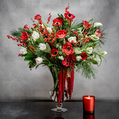 Christmas arrangement with red anemones, white tulips, Ilex berries, and winter greens
