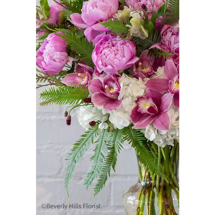Elegant Floral Fusion arrangement with peonies, cymbidium orchids, and white hydrangeas in a tall glass vase – available for same-day delivery by Beverly Hills Florist.