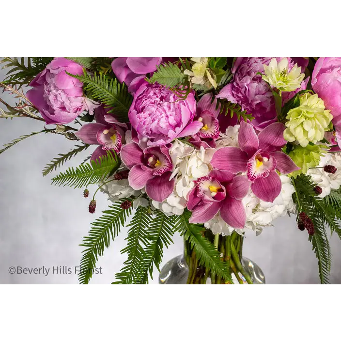 Elegant Floral Fusion arrangement with peonies, cymbidium orchids, and white hydrangeas in a tall glass vase – available for same-day delivery by Beverly Hills Florist.
