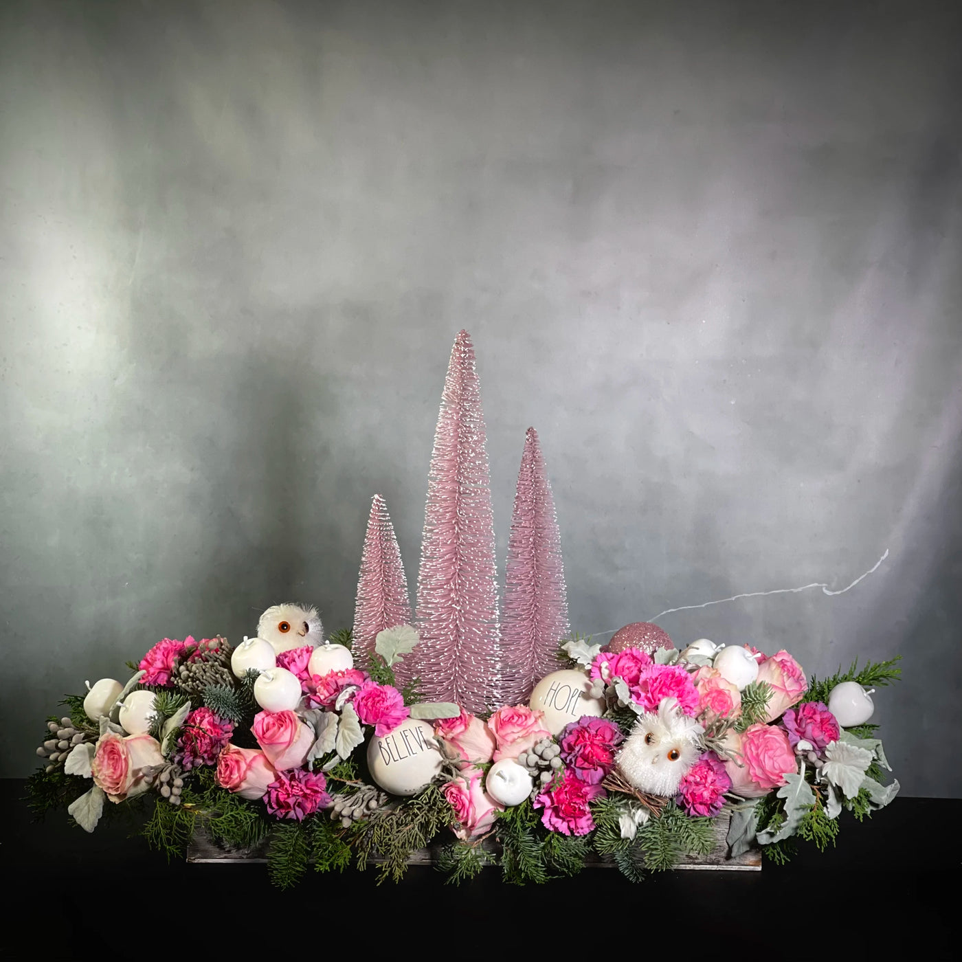 Pink Christmas arrangement featuring orchids, pink peonies, white hydrangeas, and holiday greens in a rectangular ceramic vase, available for same-day delivery by Beverly Hills Florist.