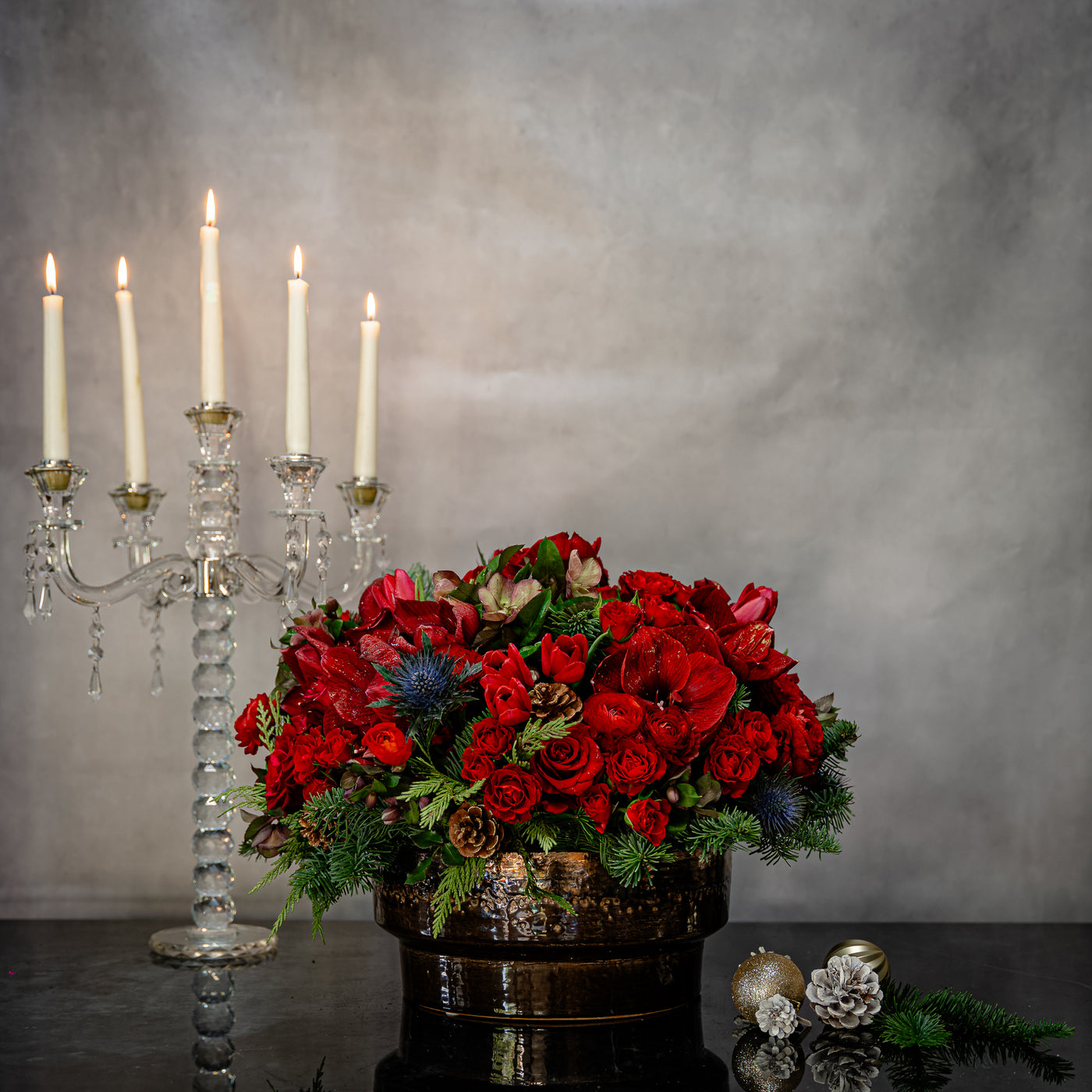 Round Christmas Gift Box with roses, amaryllis, thistle, tulips, orchids, seasonal greens, berries, pine cones, and champagne, available for same-day delivery in Los Angeles.