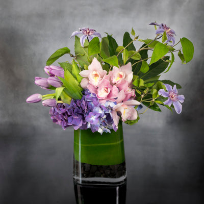 My Beverly Hills Florist offers same day delivery for our arrangements. This piece includes purple Hydrangeas, pink Orchids, purple Tulips and seasonal greens. Beautifully arranged for an office or a modern touch for any home with a pop of color. 