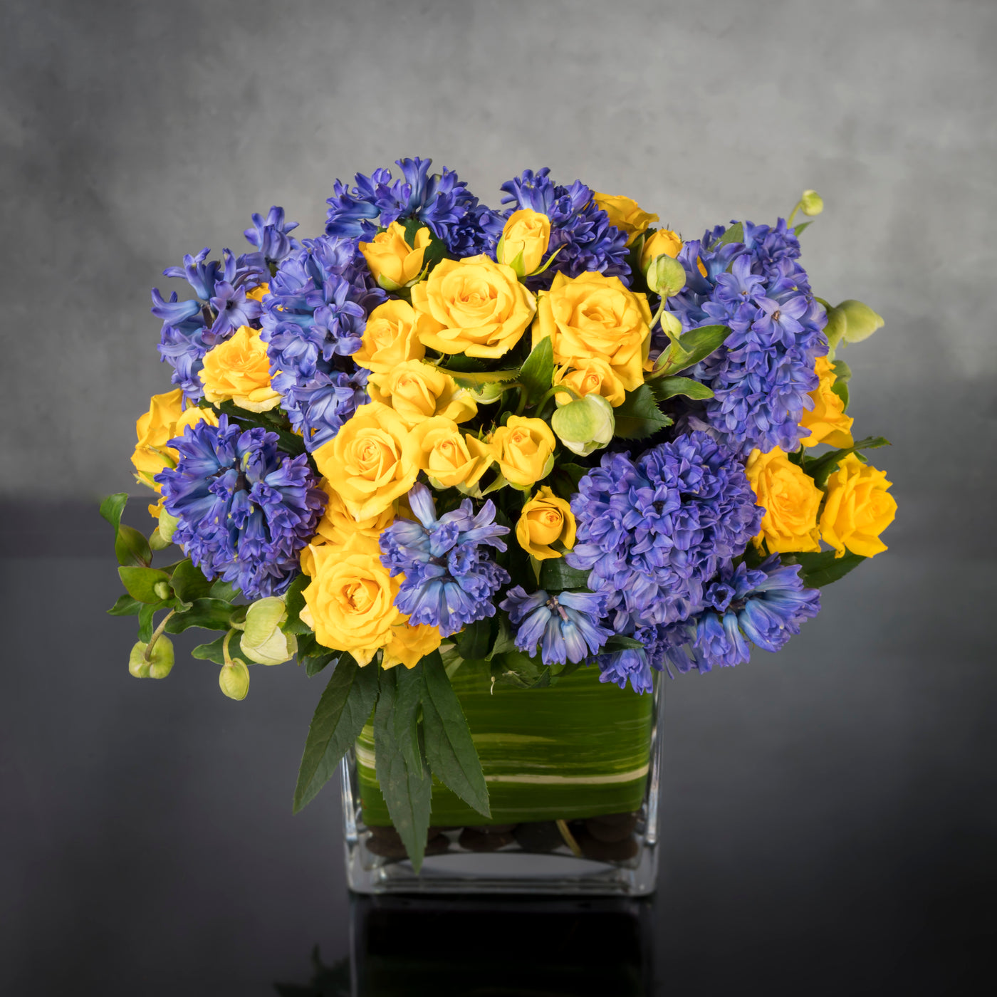 Summer Solstice features yellow spray Roses and purple Hyacinths, and seasonal flowers in a leaf-lined glass vase. This sweet, summery arrangement will bring a ray of sunshine to anyone's day. Beverly Hills Florist offers same day delivery for our summer solstice ! Blooms maybe replaced depending on the season. Perfect for the summer, thank you, thinking of you and birthday flowers! 