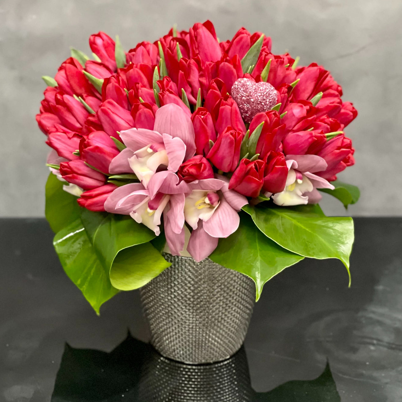 50 Beautiful dress-up pink Tulips from Beverly Hills Florist that stand tall and are available for same day delivery! Placed in beautiful modern silver vase. Orchids and greens at its base add to the beauty and delight of this sweet design. A chic and contemporary look that's a great choice for many occasions. This arrangement becomes approximately  10" W x 16" H. Birthday flowers, thank you flowers, get well flowers, congratulations flowers