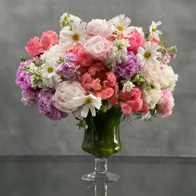 This pedestal glass vase bursts with blooms of gorgeous pinks, and sprinkles of white in a stunning and luscious pastel floral design. Beverly hills Florist presents same day delivery for this artful and impressive arrangement. It includes fabulous Peonies, Asters and Stock. A floral gift for any occasion that will surely say, “You’re fabulous!” This piece is perfect for Love and romance. 