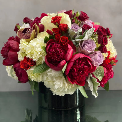 Beverly Hills Florist presents an arrangement that is sure to wow and its available for same day delivery! Our floral piece includes peonies, lavender and white and red roses, cymbidium orchids , nested on hydrangeas in a black cylinder vase. A stunning decoration for any home or office! Or a romantic gesture of love ! 
