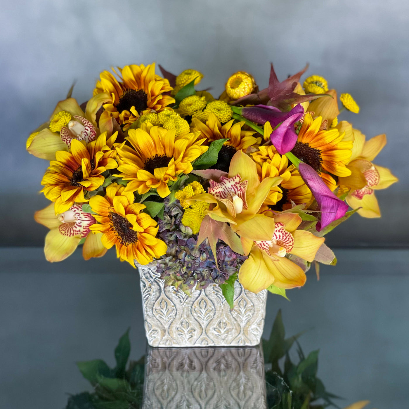 Our team presents Sunflowers hugged by antique Hydrangeas and locally grown flowers accented with imported Dutch Orchids and Call Lilies sit in a rustic 7" Square container. Beverly Hills Florist presents same day delivery ! Approx. 10" Round. Beautifully arranged for Birthdays and a touch of rustic beauty for your home. Birthday, Thank you flowers, Office, Home flowers. 