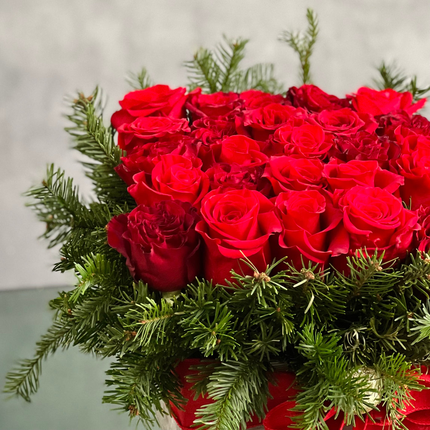 A Merry Little Christmas centerpiece with red roses, greenery, and gold ornaments, available for same-day delivery by Beverly Hills Florist.