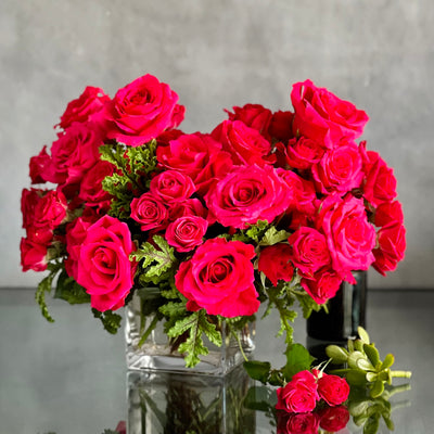 A Moment In Time arrangement with hot pink Ecuadorian roses and scented geraniums in a modern design, available for same-day delivery by Beverly Hills Florist.