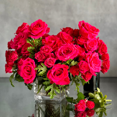 A Moment In Time arrangement with hot pink Ecuadorian roses and scented geraniums in a modern design, available for same-day delivery by Beverly Hills Florist.