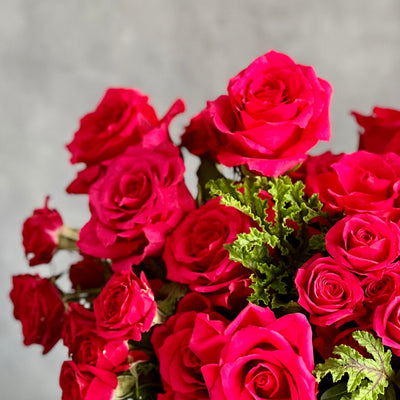 A Moment In Time arrangement with hot pink Ecuadorian roses and scented geraniums in a modern design, available for same-day delivery by Beverly Hills Florist.