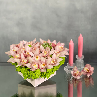 A Pink Delicate Touch arrangement with pink cymbidium orchids, hydrangeas, and succulent in a heart-shaped box, modern same-day delivery by Beverly Hills Florist.