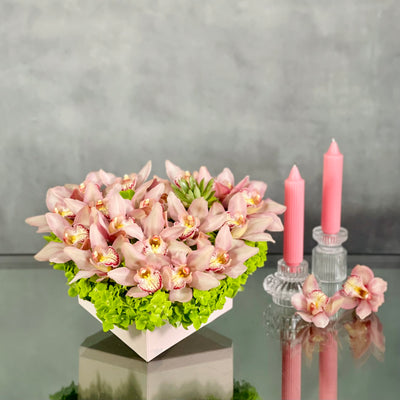 A Pink Delicate Touch arrangement with pink cymbidium orchids, hydrangeas, and succulent in a heart-shaped box, modern same-day delivery by Beverly Hills Florist.