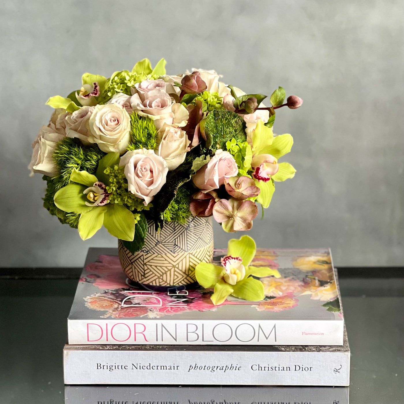 A Rustic Romance arrangement with cream roses, green cymbidium orchids, and seasonal greens in a geometric earth-toned vase, same-day delivery by Beverly Hills Florist.