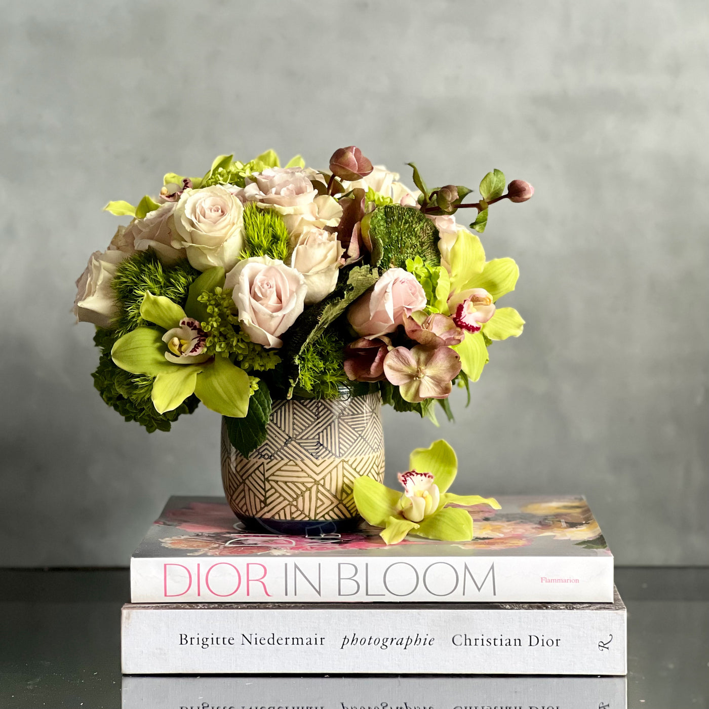 A Rustic Romance arrangement with cream roses, green cymbidium orchids, and seasonal greens in a geometric earth-toned vase, same-day delivery by Beverly Hills Florist.