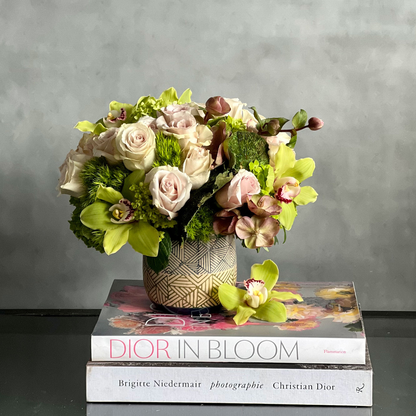 A Rustic Romance arrangement with cream roses, green cymbidium orchids, and seasonal greens in a geometric earth-toned vase, same-day delivery by Beverly Hills Florist.