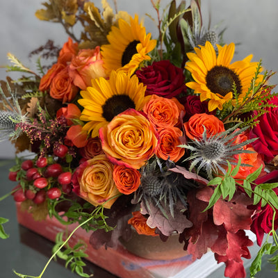 Autumn in the Air arrangement with orange, yellow, and red roses, sunflowers, and fall foliage in a ceramic vase, available for same-day delivery in 90210.