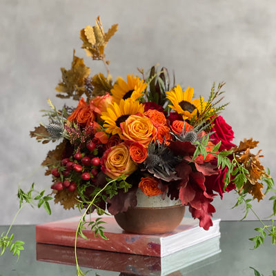 Autumn in the Air arrangement with orange, yellow, and red roses, sunflowers, and fall foliage in a ceramic vase, available for same-day delivery in 90210.