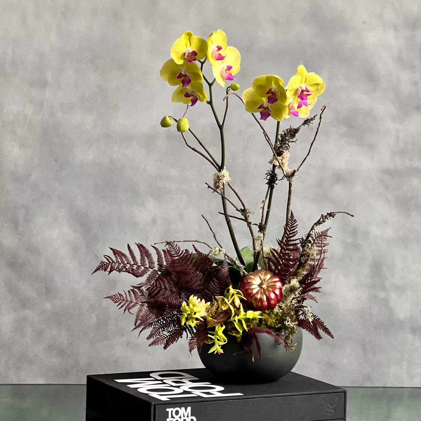 Beautiful as Always double yellow orchids with fall accents in a modern matte black ceramic bowl, available for same-day delivery by Beverly Hills Florist.