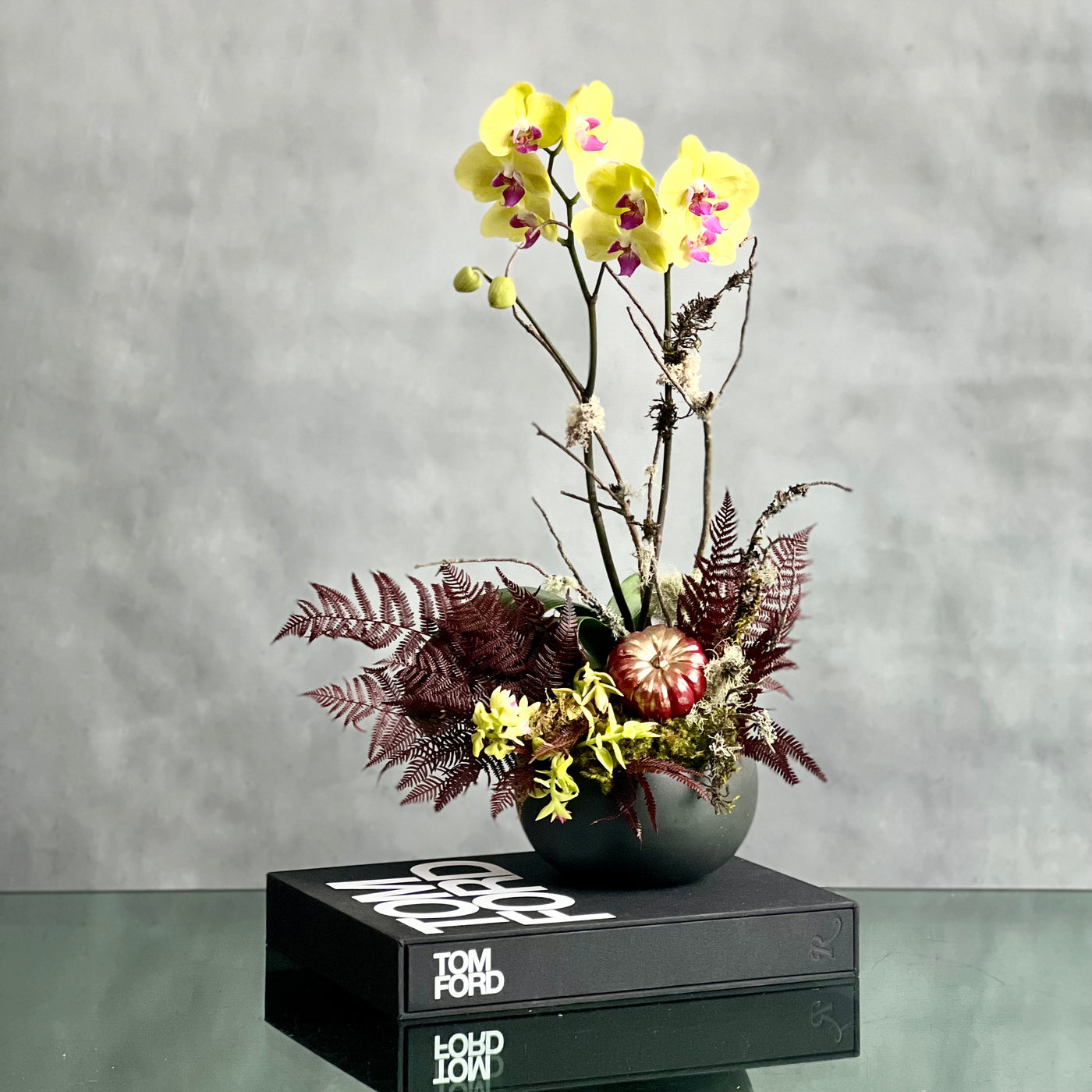 Beautiful as Always double yellow orchids with fall accents in a modern matte black ceramic bowl, available for same-day delivery by Beverly Hills Florist.