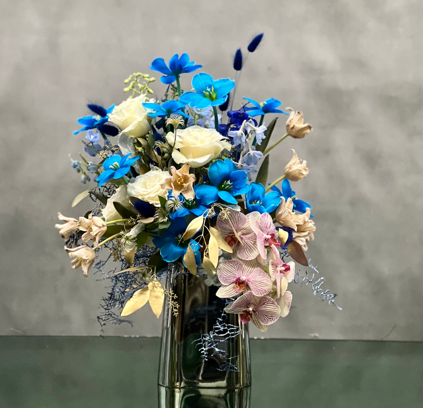 Same day delivery from beverly hills florist. Includes blue Tulips, Orchids, seasonal greens placed in a modern vase. 