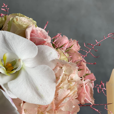 Dancing on the Clouds arrangement featuring soft pink hydrangeas, roses, spray roses, and white orchids in a chic white ceramic vase, perfect for all occasions.