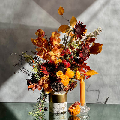 Elegant fall floral arrangement with Dutch Orchids, Black Sunflowers, berries, branches, fall foliage, mini pumpkins, and locally grown flowers in a marble gold container.