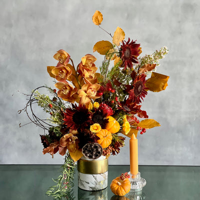 Elegant fall floral arrangement with Dutch Orchids, Black Sunflowers, berries, branches, fall foliage, mini pumpkins, and locally grown flowers in a marble gold container.