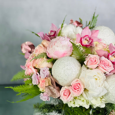 Pink Holiday arrangement featuring pink orchids, peonies, roses, and winter greens in a glass vase, available for same-day delivery by Beverly Hills Florist.