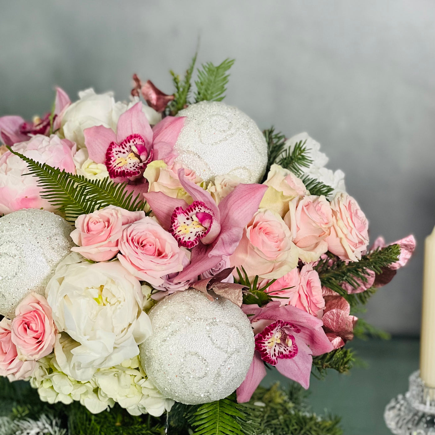 Pink Holiday arrangement featuring pink orchids, peonies, roses, and winter greens in a glass vase, available for same-day delivery by Beverly Hills Florist.