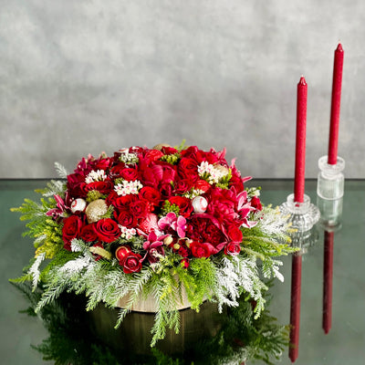 Round Christmas Gift Box featuring roses, peonies, orchids, holiday greens, berries, and pine cones in a decorative round box, available for same-day delivery by Beverly Hills Florist.