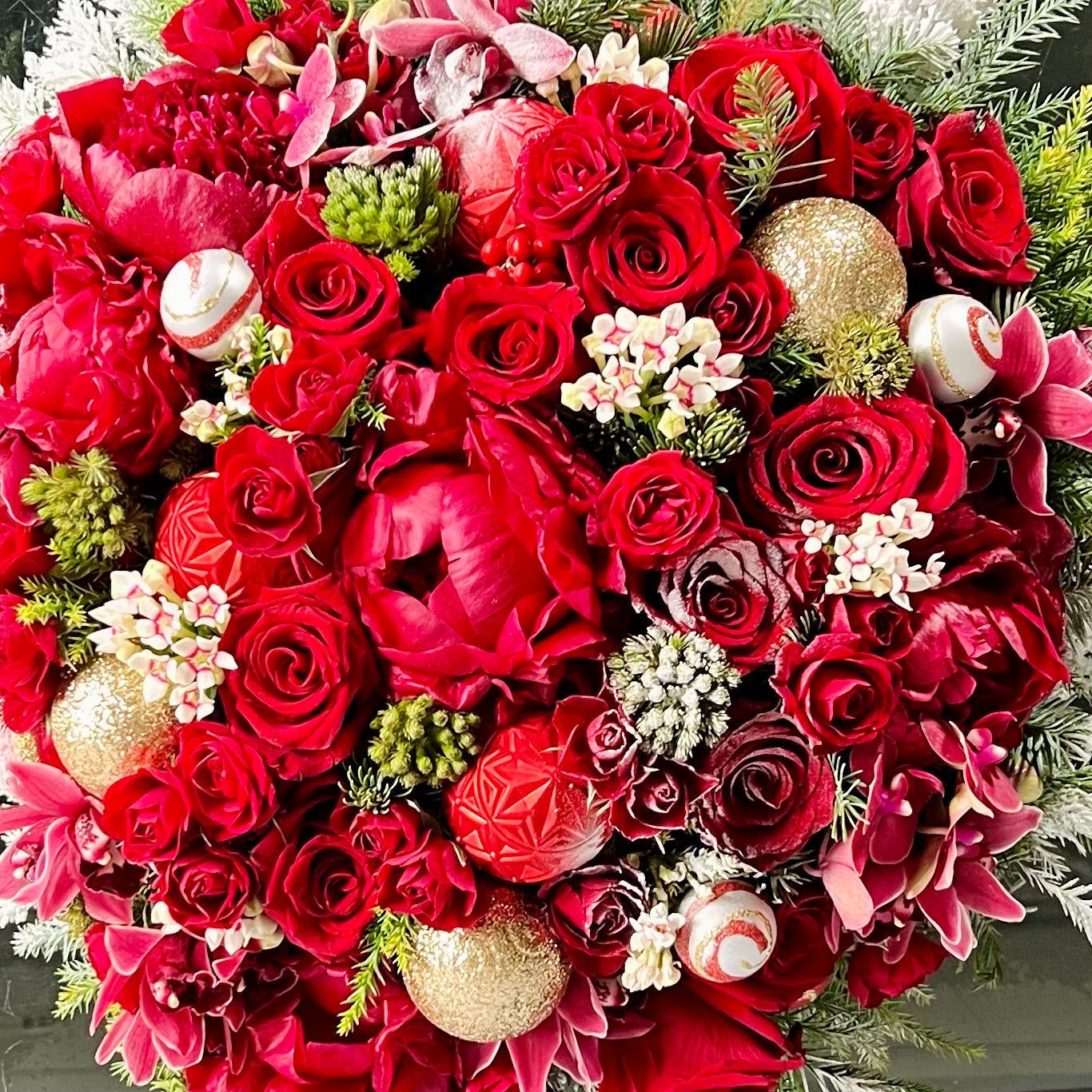 Round Christmas Gift Box featuring roses, peonies, orchids, holiday greens, berries, and pine cones in a decorative round box, available for same-day delivery by Beverly Hills Florist.