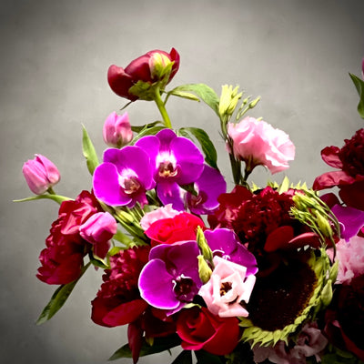 Luxurious Burgundy peony, lavender tulip, and purple orchid arrangement in a silver container with pale green accents, same-day delivery Beverly Hills.