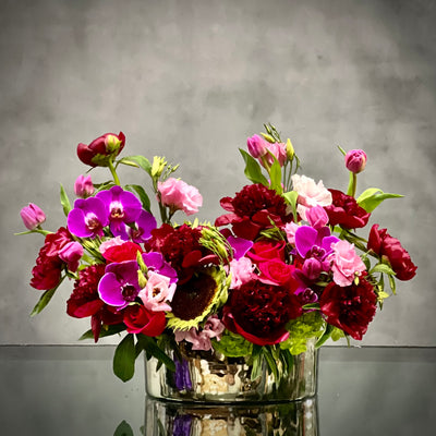 Luxurious Burgundy peony, lavender tulip, and purple orchid arrangement in a silver container with pale green accents, same-day delivery Beverly Hills.
